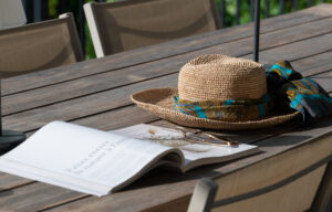 Zonnehoed, zonnebril en een opengeslagen boek op een houten tafel