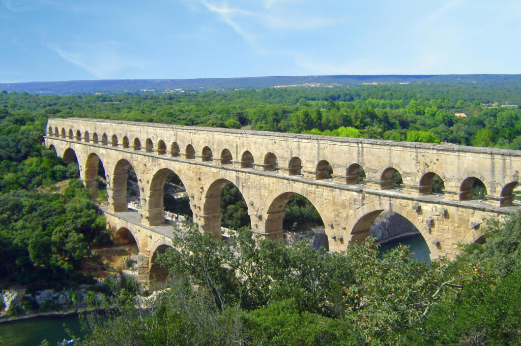 Pont du Gard gezien over de lengte, met het Romeinse viaduct en de uitgestrekte bossen erachter.