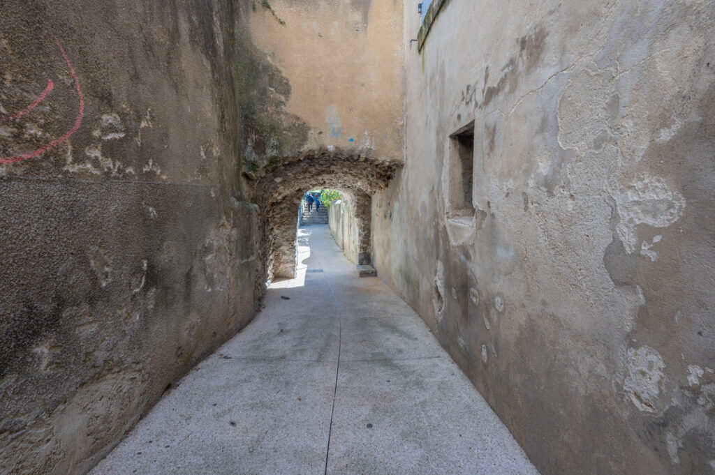 Ancienne porte en pierre à Nyons, où les visiteurs doivent se baisser pour entrer dans le centre historique par une ruelle étroite.
