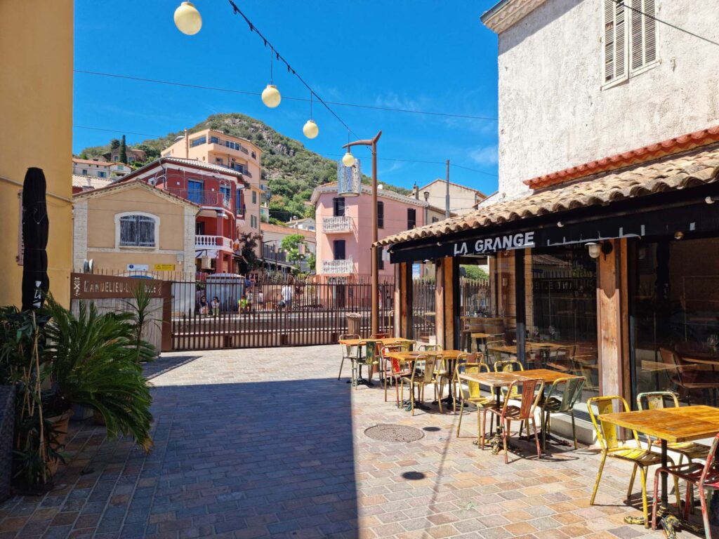 Centre de La Napoule avec passage à niveau et commerces et terrasses environnants.