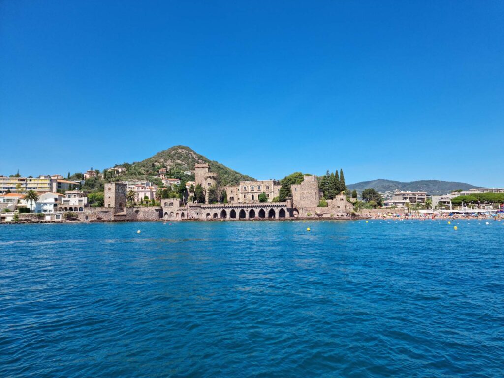 View of Château de La Napoule from the water, with the coastline of Mandelieu-La-Napoule in the background.