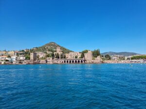 View of Château de La Napoule from the water, with the coastline of Mandelieu-La-Napoule in the background.