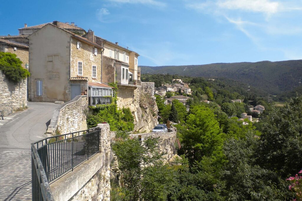 Sfeervol straatje in Bonnieux met oude pandjes en een prachtig uitzicht op de beboste berghellingen van de Luberon.