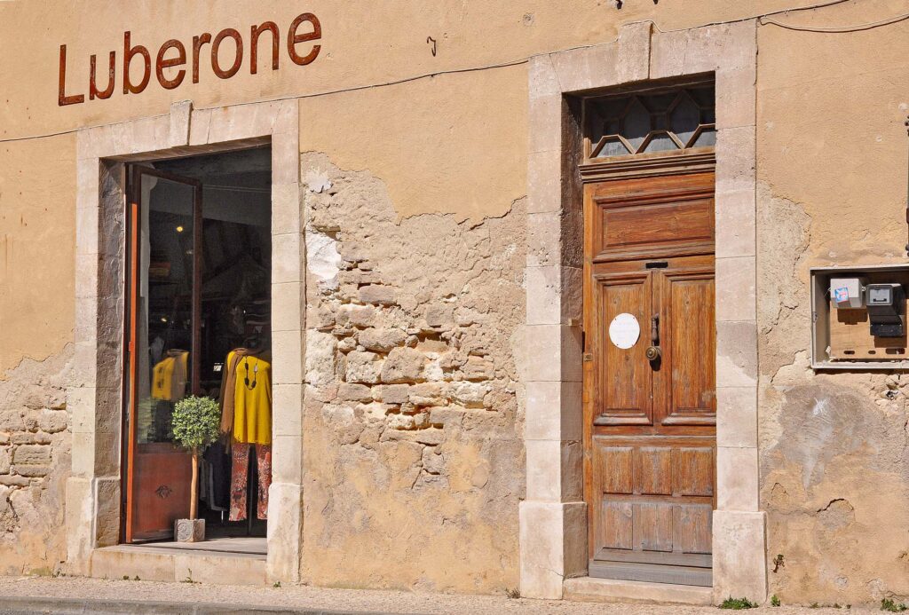 Charmant winkeltje ‘Luberone’ in Bonnieux met een okerkleurige gevel en een oude houten deur.