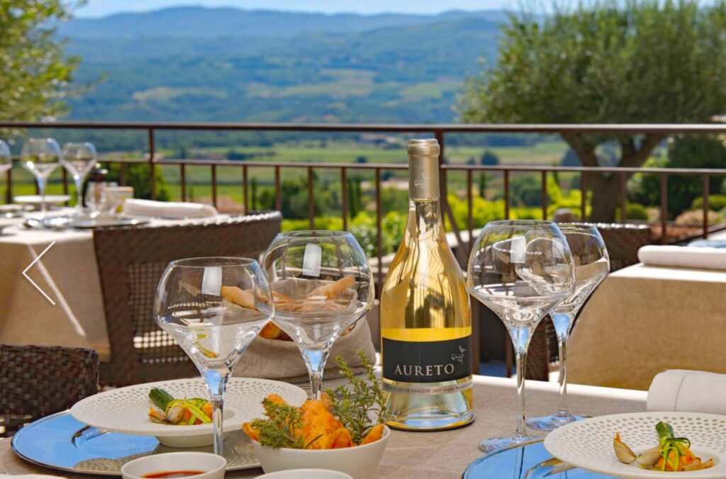 Gezellig gedekte eettafel met wijnglazen en prachtig uitzicht over de heuvels van de Luberon.