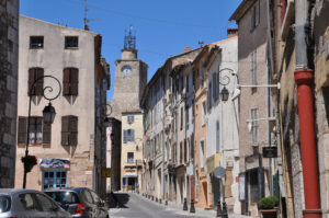 Narrow street in Lorgues with old buildings and the church tower in the background