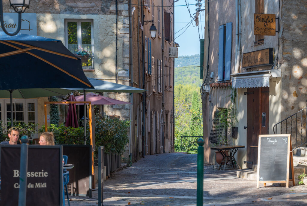 Charming street view in Flayosc with old stone houses, a restaurant terrace and mountain view in the Var, Provence