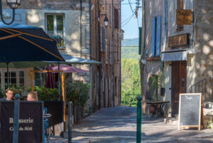 Charmante rue vue à Flayosc avecen vieilles pierres, terrasse de restaurant et vue sur les montagnes dans le Var, en Provence