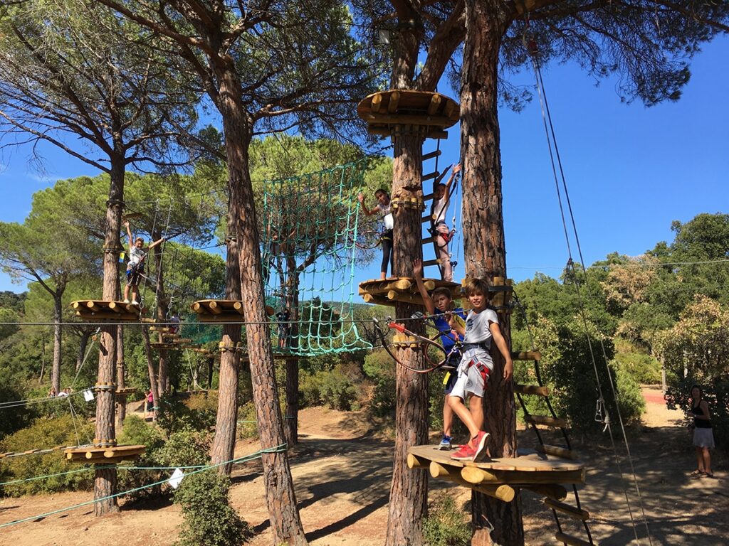 Kinderen met helm en veiligheidstuigje op het lage kinderparcours van klimpark Aventure Famille in Sainte-Maxime.