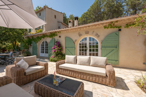 Elegant lounge terrace of La Bergerie Caseneuve in Cotignac with stone façade and view over the private estate.