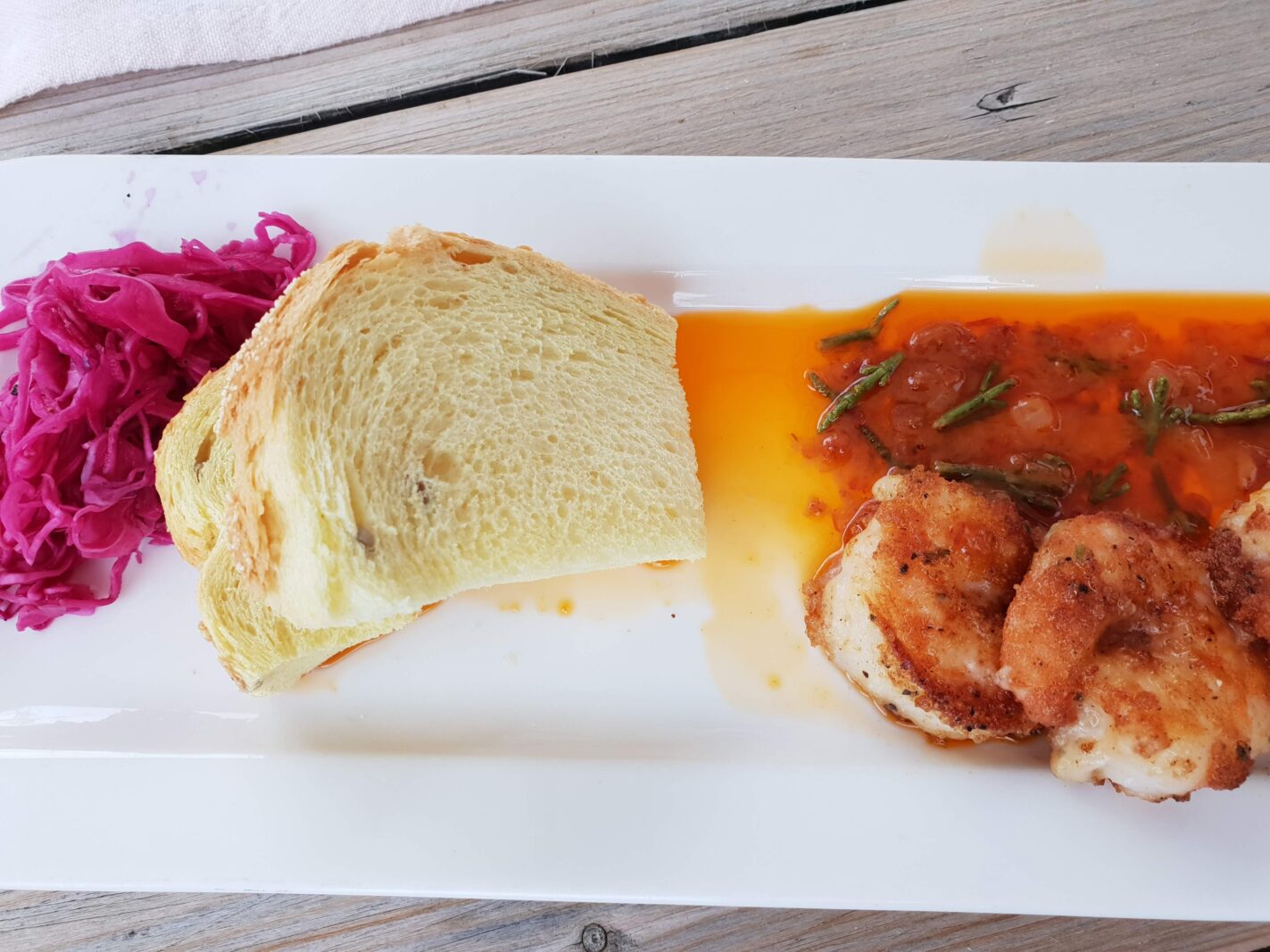 Kleurrijk gerecht met paarse bietjes, brood en vlees in saus op een wit bord