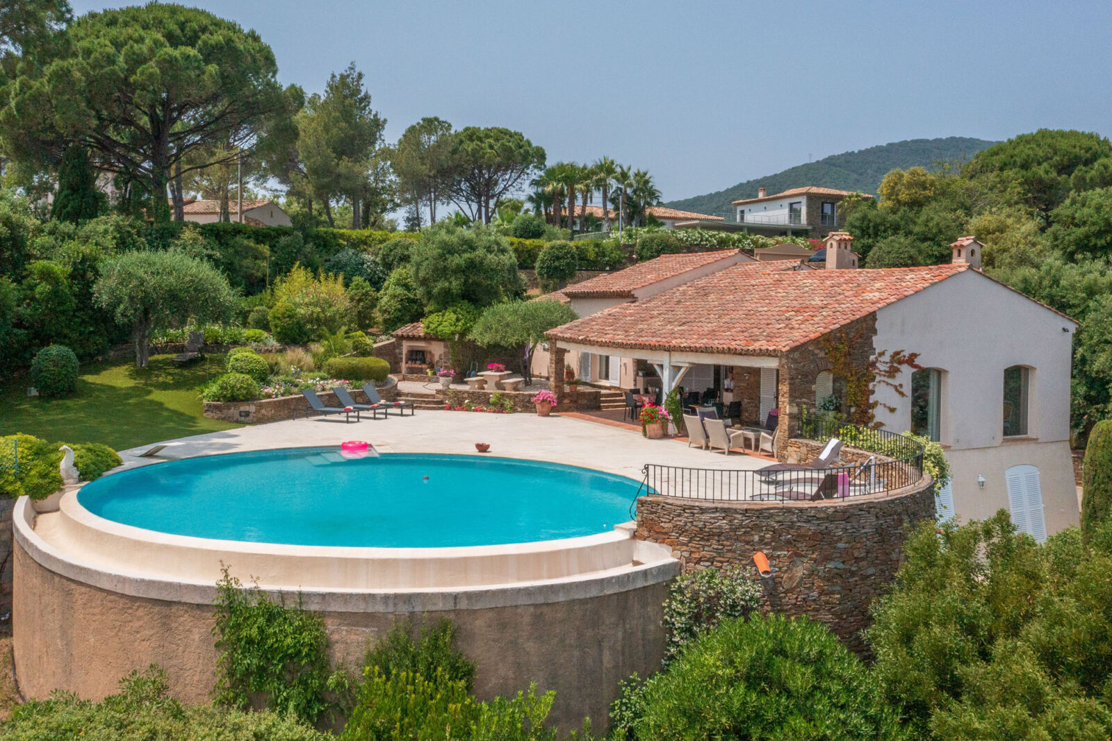 Luchtfoto van Villa La Baraka in Sainte-Maxime met rond overloopszwembad, duikplank, tuin en overdekte terrassen