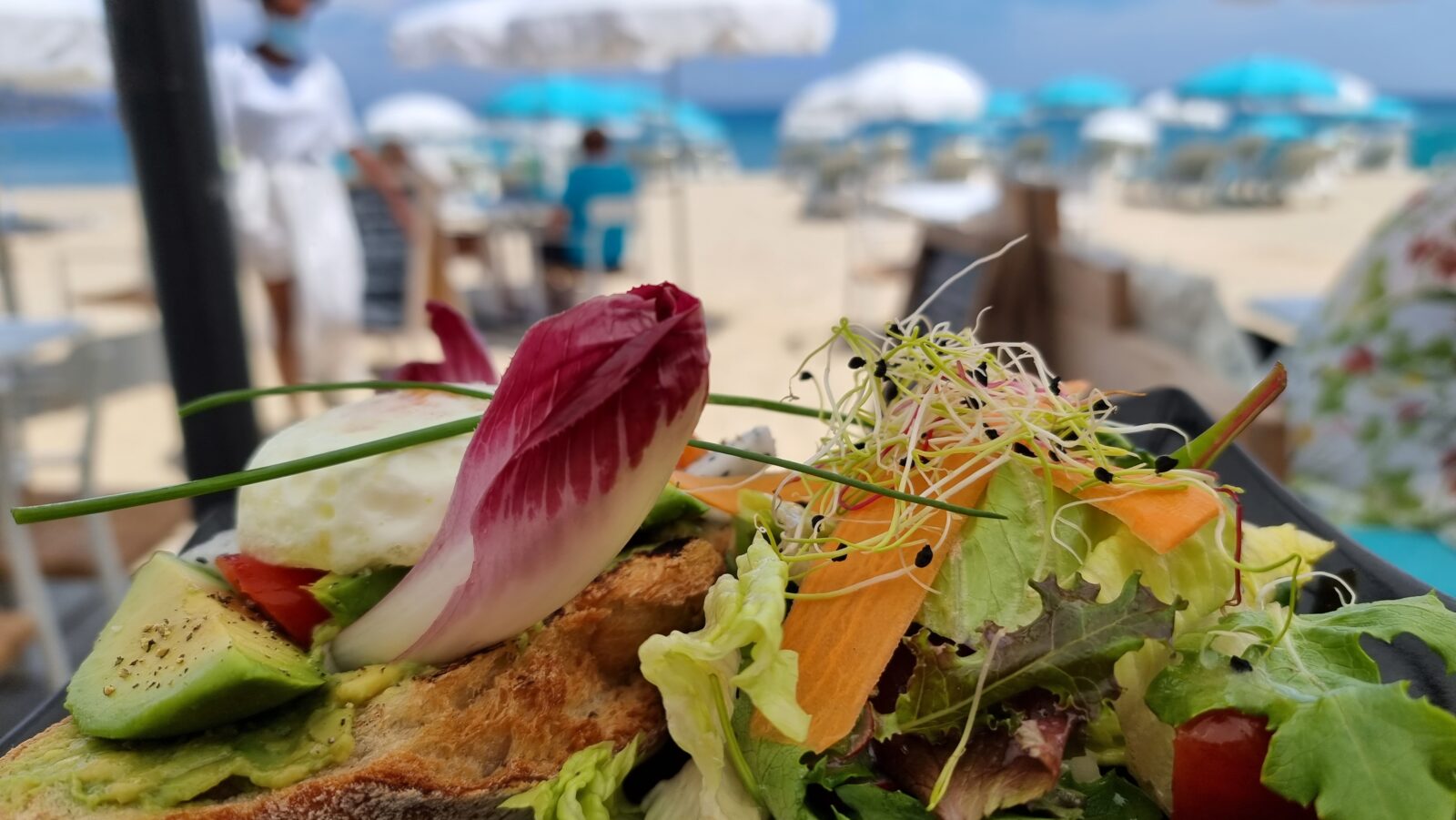 Salade bij Barco Beach in La Nartelle met strand en blauw-witte parasols op de achtergrond